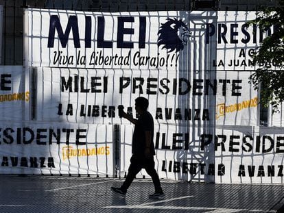 Un hombre camina fuera del Congreso argentino, cubierto por mantas a favor de Javier Milei, en Buenos Aires.