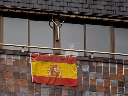 Una vecina de Carabanchel se asoma el pasado viernes a la ventana, en la que ha colocado una bandera de España.