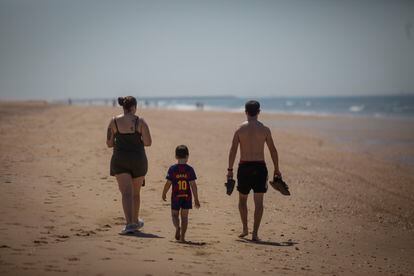 Una familia pasea por la playa de Punta Umbría (Huelva).