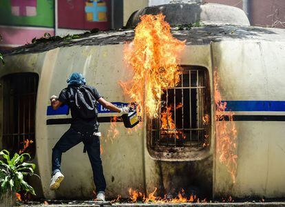 Un manifestante de la oposición prende fuego a un puesto policial durante los disturbios.