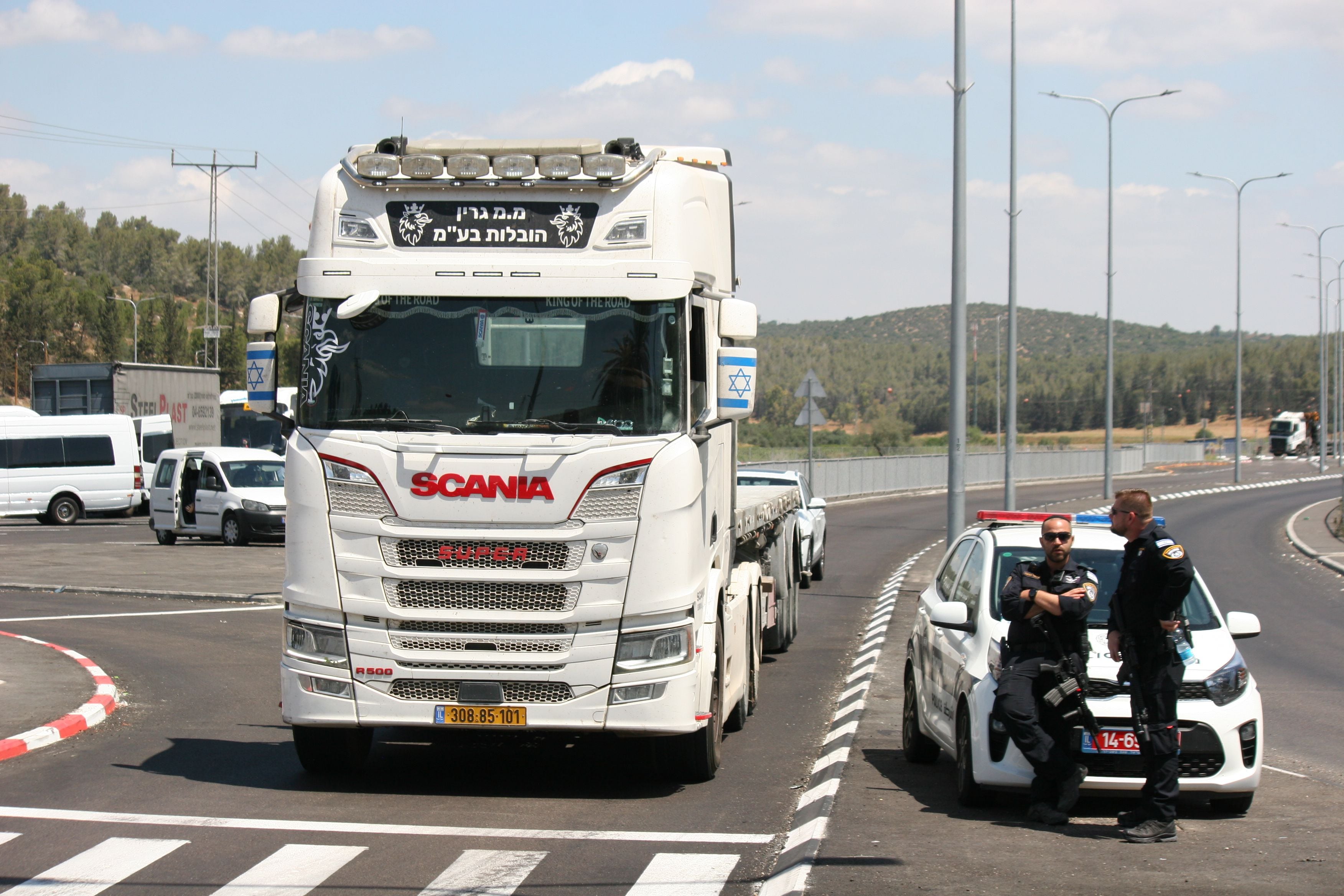 Dois policiais vigiam a passagem de caminhões em Tarqumiya, em frente à “guarda humanitária” de uma ONG pacifista, no mês passado.