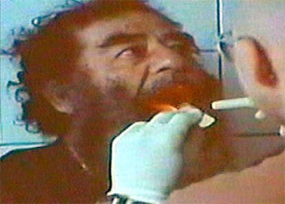 Un oficial examina la dentadura de Sadam Husein, en una imagen tomada del vídeo de su captura.