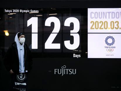 Un hombre pasa ante un reloj con la cuenta atrás para el teórico inicio de los Juegos de Tokyo.