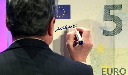 El ex presidente del Banco Central Europeo, Mario Draghi, firmando un billete de cinco euros.