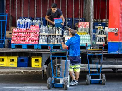 Dos repartidores bajan paquetes de bebidas de un camión en Madrid.