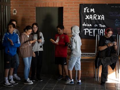 Varios alumnos del intituto escuela Feixes, en Terrassa (Barcelona), consultan el móvil durante la pausa del recreo.
