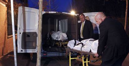 Dos hombres retiran los cuerpos sin vida de una pareja hallada muerta en Fuenlabrada.