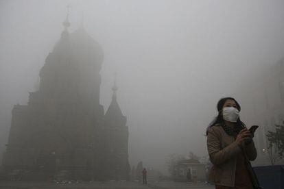 Una mujer junto a la iglesia de San Sofía en Harbin (China), 21 de octubre de 2013. La niebla tóxica ha provocado el cierre de las escuelas y el corte de algunas carreteras, según informa la agencia estatal china Xinhua.