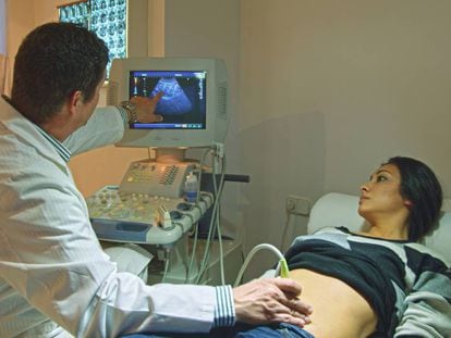 Un médico realiza una ecografía a una mujer.