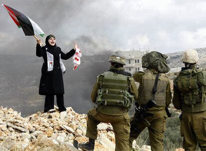 Una joven palestina se manifiesta frente a  tres soldados israelíes en la localidad de Bilin, cercana a Ramala, en Cisjordania, durante una protesta contra la ofensiva en Gaza.