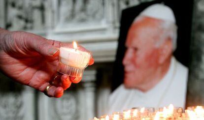 Una persona enciende una vela ante una imagen del papa Juan Pablo II en la catedral de Saint G&ouml;dele de Bruselas.