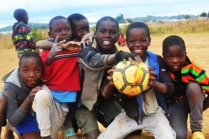 Un grupo de niños posa con un balón en el campo de fútbol de Bauleni, Lusaka.