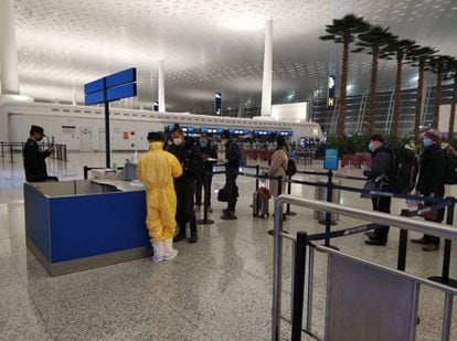 Personal del aeropuerto realiza en el embarque el control de seguridad a los españoles atrapados en Wuhan.