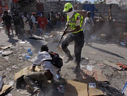 Un policía haitiano apunta a una de las personas presentes en las zonas saqueadas.