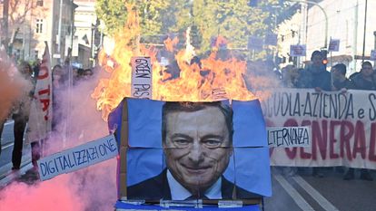 Estudiantes prenden fuego a un póster del primer ministro italiano, Mario Draghi, durante una protesta en Turín convocada con motivo de la jornada de huelga general que vive el país.