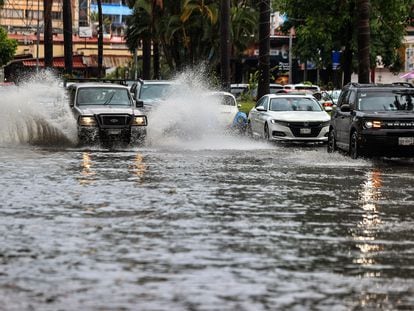 Vehículos transitan por una calle inundada en Acapulco, Guerrero, debido a las lluvias provocadas por el huracán Hilary.