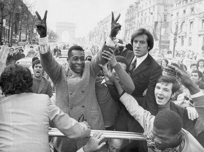 El futbolista brasileño alza los brazos mientras recorre los Campos Elíseos de camino a una recepción en el Ayuntamiento de París en 1971.