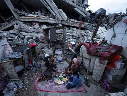 Miembros de la familia Al-Rabaya rompen el ayuno durante el mes del Ramadán frente a su casa destruida por los ataques aéreos israelíes en Rafah, este lunes.