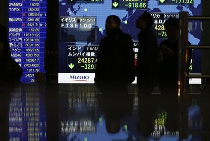 Peatones ante un monitor de cotizaciones en Tokio.