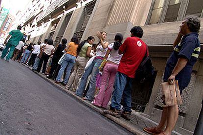 Un grupo de inmigrantes hace cola en la oficina de extranjería de la calle de Los Madrazo, en Madrid.