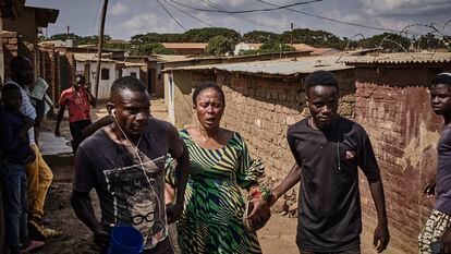 Unos hombres ayudan a una habitante del campamento de refugiados de Dazleka (Malaui) embarazada después de que un bote de gas lacrimógeno entrara en su casa, el pasado mes de febrero.
