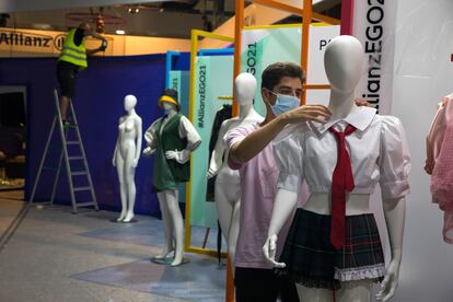 Un joven coloca ropa a un maniquí en la Mercedes-Benz Fashion Week Madrid, en IFEMA.