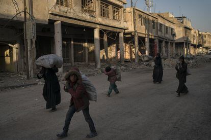 Niños y mujeres cargan sacos de metal recogidos de entre la basura en la Ciudad Vieja de Mosul.