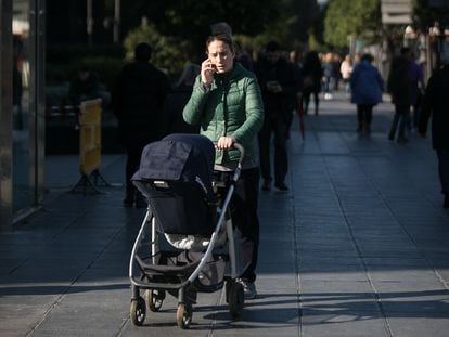 Una mujer pasea con un carrito de bebé por una calle de Barcelona.