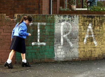 Una escolar passa per davant d'una pintada de l'IRA a l'àrea de Newlodge del nord de Belfast.
