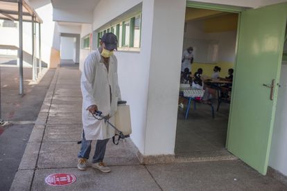 Un empleado desinfecta el suelo de un colegio en Rabat el 8 de septiembre mientras los alumnos atienden a la profesora en una clase.