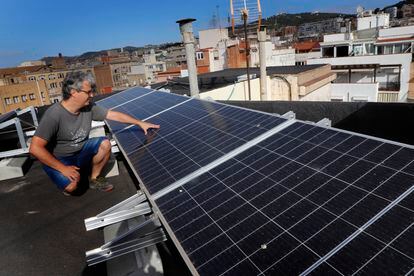 Eduard Moreno, ante los paneles fotovoltaicos que ha instalado en la cubierta del edificio donde vive, en el barrio de Gràcia de Barcelona en julio.
