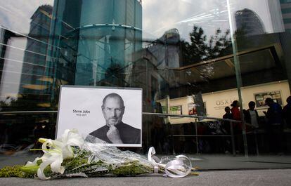 Un ramo de flores junto a una imagen de Steve Jobs en una tienda Apple de Shanghay.