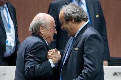 El presidente de la FIFA, Josep Blatter (izquierda), estrecha la mano del presidente de la UEFA, Michel Platini, en la asamblea de la FIFA celebrada en Zúrich el 29 de mayo, apenas unas horas después de que la justicia de EE UU y Suiza destaparan una trama de corrupción en el organismo que dirige el fútbol mundial y detuvieran a siete directivos por aceptar sobornos durante 24 años. | <a href="http://elpais.com/hemeroteca/elpais/2015/05/29/n/portada.html" target="blank"> IR A LA NOTICIA</a>