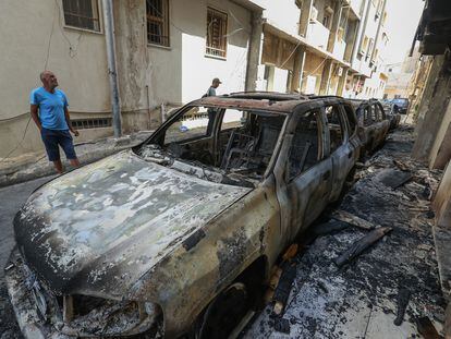 Vecinos observan los vehículos calcinados tras los enfrentamientos armados registrados en Trípoli el pasado 28 de agosto.