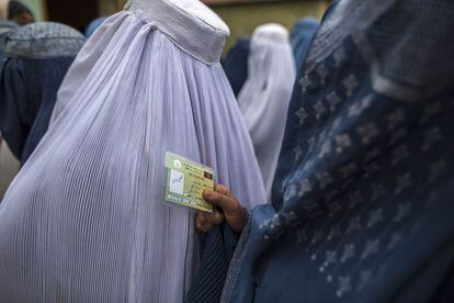 Una mujer sujeta su tarjeta para poder votar en las elecciones presidenciales en la ciudad de Mazar-i-sharif.