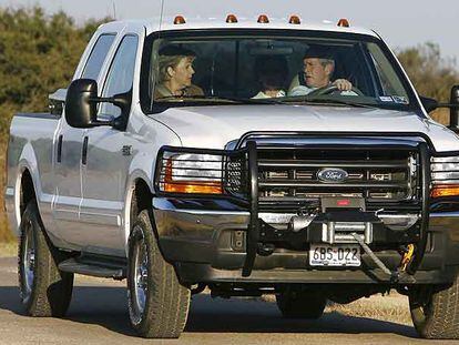 Angela Merkel, George Bush y Laura Bush (detrás), ayer en coche por el rancho de Crawford (Tejas).