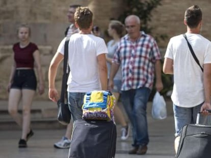 Cuatro turistas caminan con su maletas por Valencia.