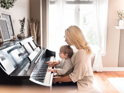 Un niño toca el piano con su madre.