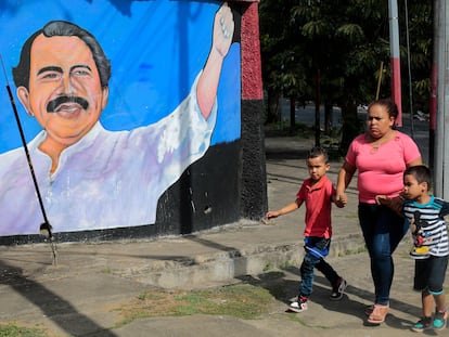 Una mujer pasea con sus hijos delante de un mural de Daniel Ortega, este lunes en Managua.