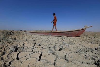 Un niño camina en un bote dejado sobre el lecho seco de una sección de las marismas del sur de Irak de Chibayish, en la provincia de Dhi Qar, el 28 de junio de 2022.