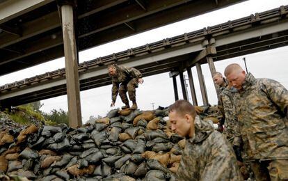 Miembros de la Guardia Nacional de Carolina del Norte apilan sacos de arena debajo de un paso elevado cerca del río Lumber.