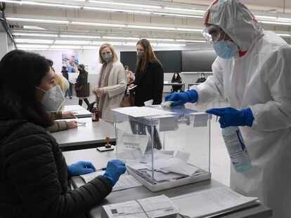 Un trabajador desinfecta una urna electoral en un colegio de Barcelona.