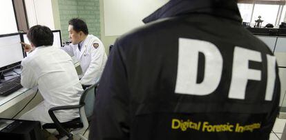 Técnicos informáticos surcoreanos comprueban un ordenador del Korean Broadcasting System ante un forense en el centro de respuesta al terror cibernético de Seúl.