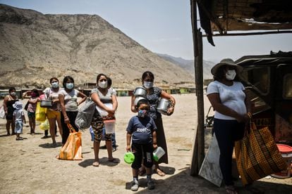 Un grupo de personas esperan recibir alimentos del comedor social de Comas, en la periferia de Lima.