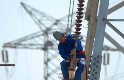 Un trabajador instala nuevas l&iacute;neas de alto voltaje en una torre de electricidad.