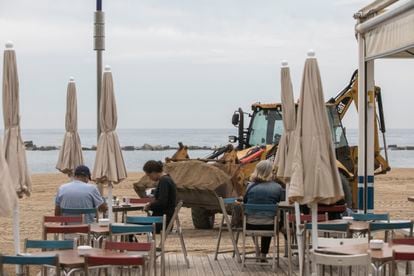 Una retroexcavadora repone arena en la playa de la Barceloneta