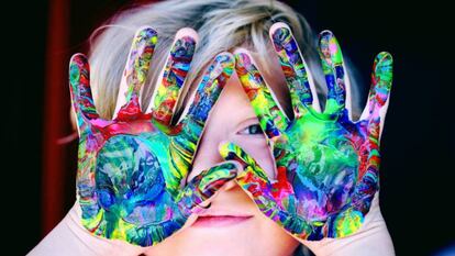 Un niño muestra sus manos pintadas.