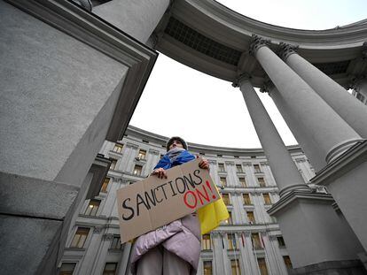 A protester holds a placard during a rally outside of Ukrainian Ministry of Foreign Affair in Kyiv on February 21, 2022 during the action "Turn sanctions ON!". - Protesters demand immediate blockade of the Nord Stream 2 project, the deepening of sanctions against Russia's energy sector, the exclusion of Moscow from the SWIFT financial system and the imposition of other sanctions already in place to curb Russia's aggression. (Photo by Sergei SUPINSKY / AFP)