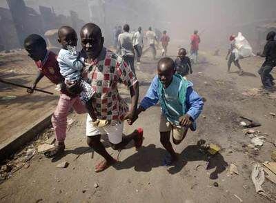 Un hombre conduce ayer a un grupo de niños fuera del suburbio de Mathare, en Nairobi, tras varios días de violencia.