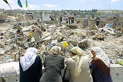 Mujeres palestinas miran la montaña de ruinas en que han quedado convertidas algunas casas del campo de refugiados de Yenín.